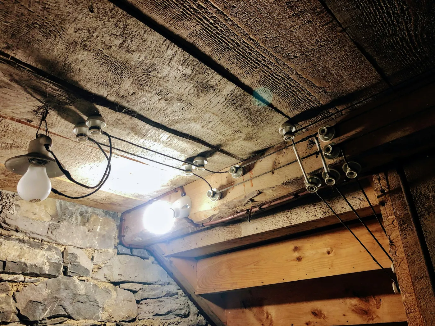 Glødepærer i taket i et gammelt hus med tømmer og steinmur.