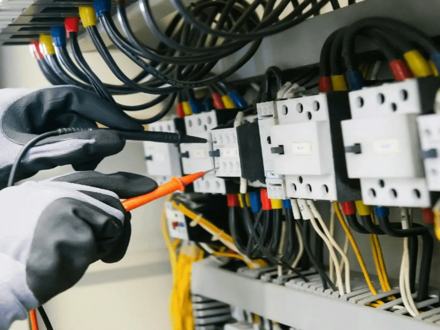 Elektriker måler i et åpent sikringsskap med multimeter.